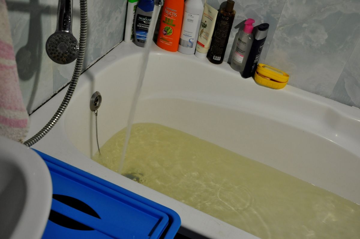 Желтая вода течет в ванну из крана